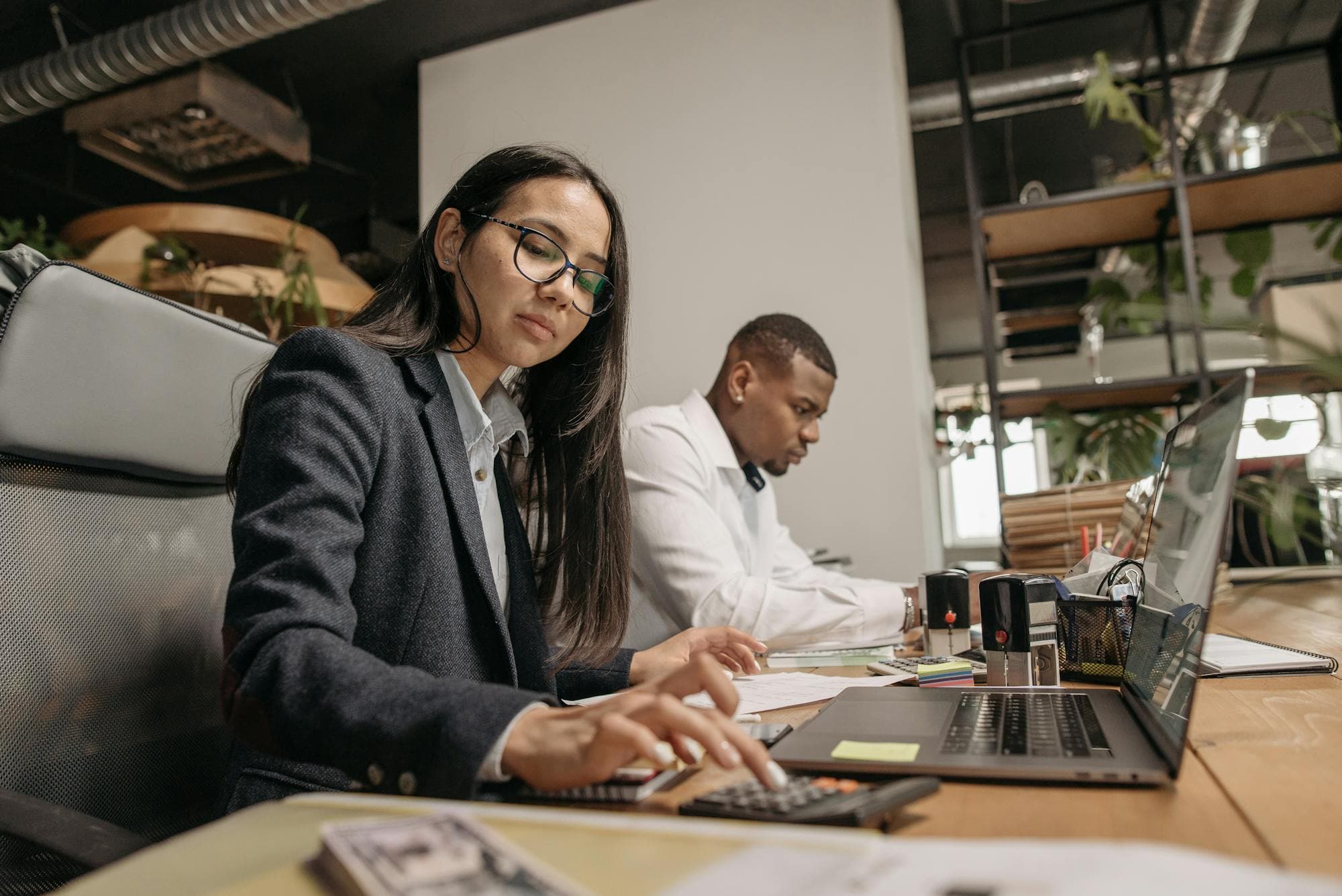 Tax professionals working with a calculator and laptop in a modern office